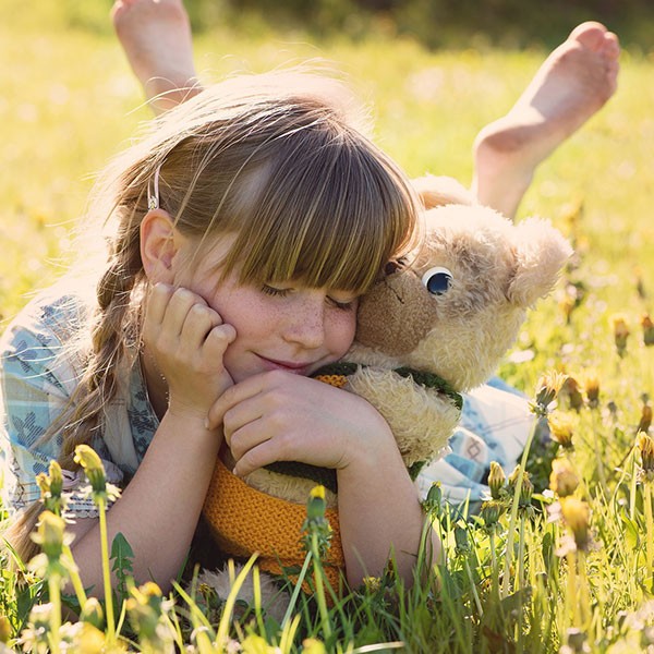 Psicología infantil - Niña en el campo con un peluche
